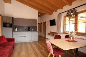 フューゲンにあるHochleger Appartement Zillertal FUZ1001のキッチン、リビングルーム(テーブル、赤いソファ付)