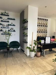 a room with a piano and green chairs and plants at Sun Sea Center in Eilat