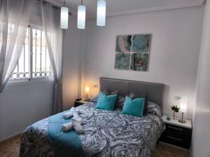 a bedroom with a bed with blue pillows and a window at Modern Duplex with Solarium Community Pool in Orihuela Costa in Orihuela +37 photos