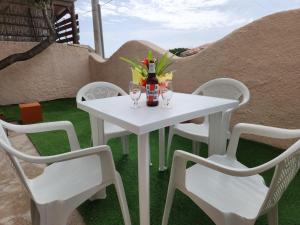 Una mesa blanca y sillas con una botella y vasos. en Casa MedeFaby, en S'Archittu
