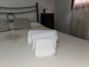 Una cama con toallas blancas encima. en Casa MedeFaby, en S'Archittu