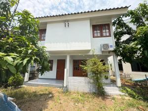 a white house with brown doors and trees at MeeboonHome in San Kamphaeng