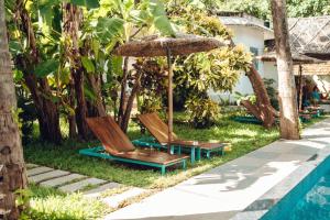 two chairs and an umbrella next to a pool at Paddle Cult Surf & Yoga in Varkala
