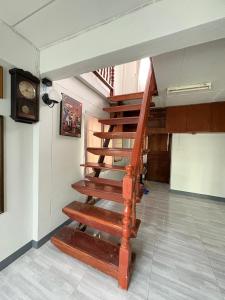 a wooden staircase in a room with a clock at MeeboonHome in San Kamphaeng