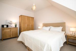 a bedroom with a large white bed and a cabinet at Ferienwohnung Abendsonne 3 in Mirow +7 photos