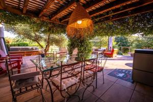 a glass table and chairs on a patio at Villa Magarre Climatisée, Piscine Chauffée, Spa, dans un Cadre Naturel Envoûtant in Castelnau-de-Montmiral
