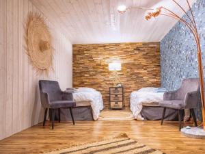 two beds in a room with two chairs and a brick wall at Villa Magarre Climatisée, Piscine Chauffée, Spa, dans un Cadre Naturel Envoûtant in Castelnau-de-Montmiral +45 photos