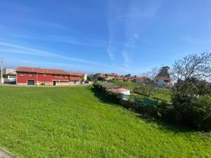 un champ d'herbe verte avec un bâtiment rouge dans l'établissement Apartamento El Baluarte, à Cudillero