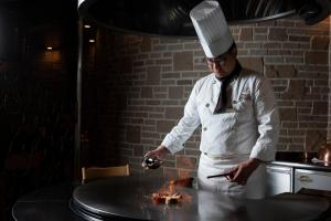 a chef preparing food on a table in a kitchen at The Prince Park Tower Tokyo - Preferred Hotels & Resorts, LVX Collection in Tokyo