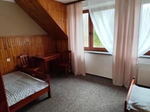 a bedroom with a desk and a table and a window at Wróbelek in Wetlina