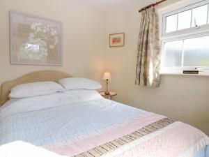 a bedroom with a large bed with a window at Grist Mill Cottage in Fontmell Magna
