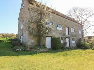 an old brick building with a tree in the yard at Grist Mill Cottage in Fontmell Magna