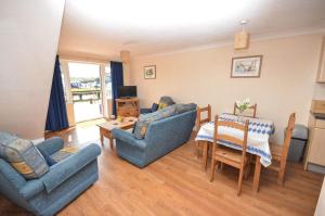 a living room with couches and a table and a dining room at Buttercup Lodge in Horning