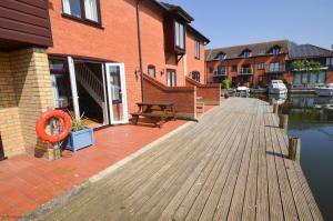 a wooden boardwalk next to a building and a river at Buttercup Lodge in Horning