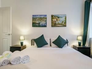 ein Schlafzimmer mit einem weißen Bett mit drei Gemälden an der Wand in der Unterkunft Luxury 2BR W Balcony Cathedral Qtr Parking! - Pass the Keys in Belfast