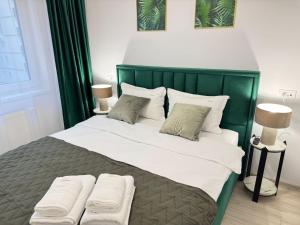 a green bed with two pillows on top of it at Coresi Area Luxury GAP Apartments in Braşov