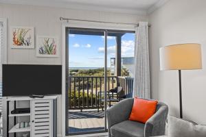 a living room with a television and a balcony at Southwinds G10 Ocean View condo in Atlantic Beach
