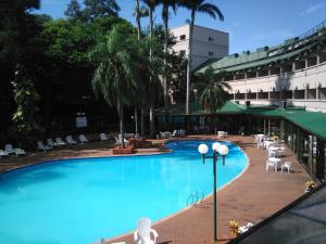 a large swimming pool with chairs and a building at Hotel El Libertador in Puerto Iguazú