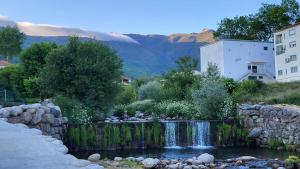 un jardin avec une cascade devant un bâtiment dans l'établissement Casa de Unhais da Serra, à Unhais da Serra