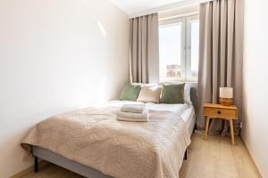 a small bedroom with a bed with a window at Wejhera Beige Chic Apartment by BookingHost in Gdańsk