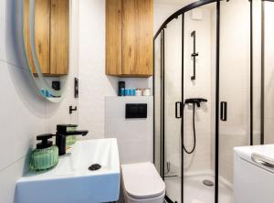 a bathroom with a shower and a sink and a toilet at Wejhera Beige Chic Apartment by BookingHost in Gdańsk +8 photos