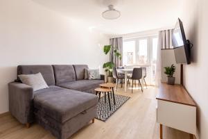 a living room with a gray couch and a table at Wejhera Beige Chic Apartment by BookingHost in Gdańsk