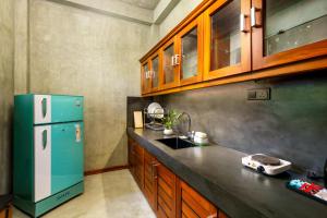 a kitchen with a green refrigerator and wooden cabinets at Villa Rumassala Luxury Chalets Unawatuna in Unawatuna