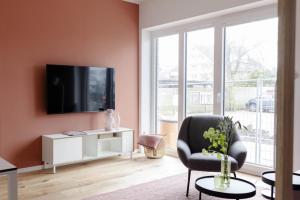a living room with a tv and a chair at Kajüte in Sankt Peter-Ording
