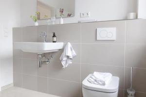 a white bathroom with a sink and a toilet at Kajüte in Sankt Peter-Ording