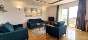 a living room with two blue chairs and a television at SEA VIEW- spacious apartment with shared pool in Split