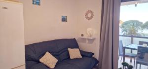 a living room with a blue couch and a balcony at Appartement climatisé avec piscine, magnifique vue mer, lac et le Pic le Canigõ ! in Le Barcarès