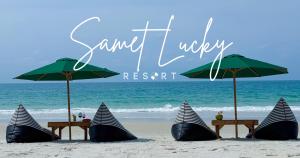沙美岛Samet Lucky Resort的海滩上的一组遮阳伞和桌子