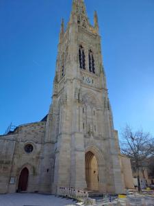 a church with a tall tower with a clock on it at Appart 2 Chambres au coeur de Libourne in Libourne