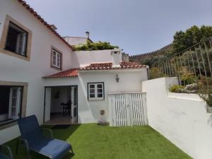 a white house with a yard with a blue chair at Casa da Biquinha in Óbidos