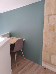 a table and chair in a room with a brick wall at Appart 2 Chambres au coeur de Libourne in Libourne