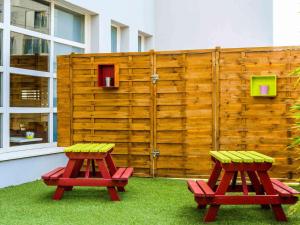 two red benches sitting next to a wooden fence at ibis budget Issy Les Moulineaux Paris Ouest in Issy-les-Moulineaux