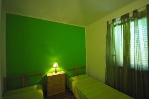zielony pokój z dwoma łóżkami i stołem z lampą w obiekcie DOLCE MARE, casa vacanze a due passi dal mare! w mieście Marsala