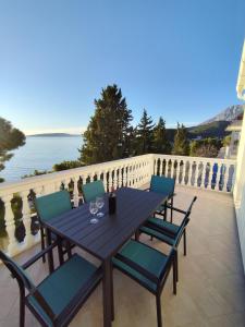 a wooden table and chairs on a balcony with the ocean at Apartments with sea view Drvenik Makarska riviera in Drvenik