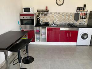 a kitchen with red cabinets and a washing machine at La Marginette in Saint-Sauveur