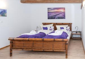a bedroom with a wooden bed with purple sheets and pillows at Gutshof Großheringen - Doppelzimmer in Großheringen +7 photos