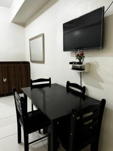 a black dining room table with a flat screen tv on a wall at Wind Suites Tagaytay Condotel in Tagaytay