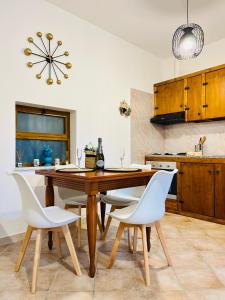 a kitchen with a wooden table and white chairs at Tyche House Castelmola in Castelmola +50 photos