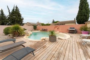 une cour arrière avec une piscine et une terrasse en bois dans l'établissement Les Dames De Molleges, à Mollégès