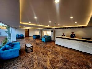 a lobby with blue couches and a bar with two men at Regenta Waterfront Resort, Dapoli in Dapoli