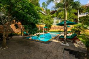 una piscina con banco y sombrilla en Villa Rumassala Luxury Chalets Unawatuna, en Unawatuna