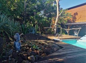 a garden with a statue next to a swimming pool at Le Tropical Lodge in Saint-Pierre