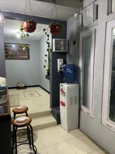 eine Küche mit einem Kühlschrank und 2 Hockern in der Unterkunft Rumahtata Homestay in Purwokerto
