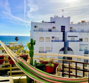 a hammock on a balcony with a building and the ocean at Sun & Fun in Armacao de Pera in Armação de Pêra