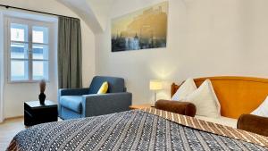 a bedroom with a bed and a chair and a window at Hotel Krone 1512 in Salzburg