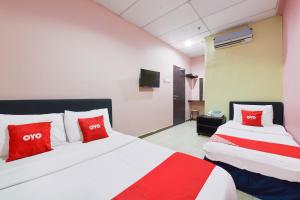 two beds with red pillows in a room at Danceter Destiny Riverside Hotel in Kota Bharu